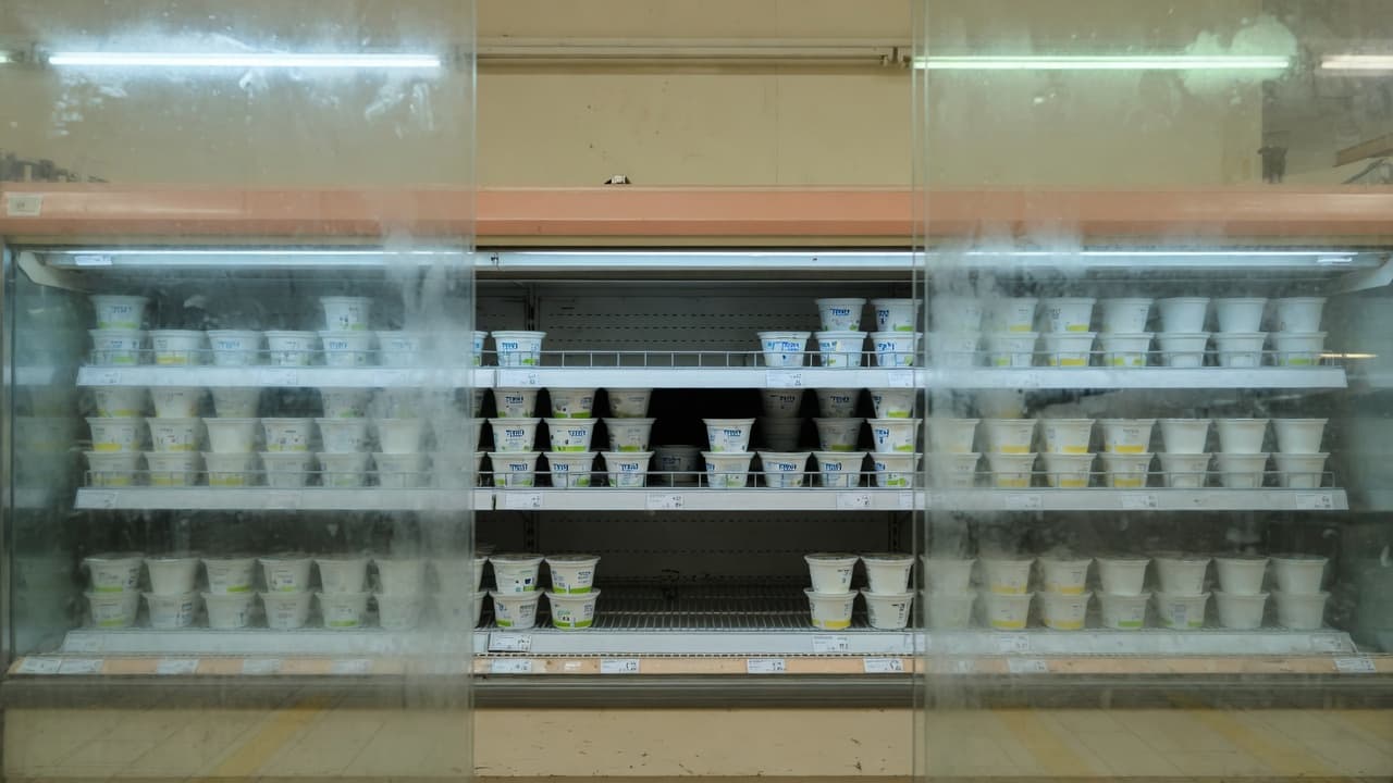 מקרר חלב בסופר עם גביעים לבנים ומדפים חסרים, בלי אנשים ובלי מספרים (בעזרת AI)